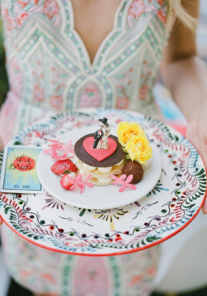 Woman holding a dessert decorated with a Catrina and a Catrin